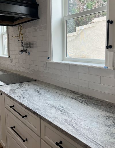 Long kitchen countertop next to a white backsplash
